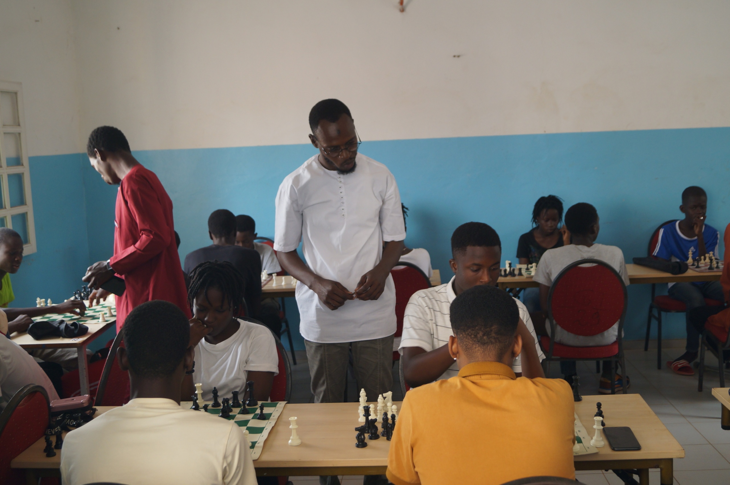 Cheikh Mbaye, 29 ans (polo blanc), bénéfice en 2016 d’une formation de l’Association Internationale des Échecs Francophones (AIDEF). Diplôme d'entraineur en 2020, aujourd'hui directeur de la Sunshine International Chess Academy (SICA), la première académie d'échecs au Sénégal.